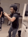 A man enthusiastically dances indoors while others watch.