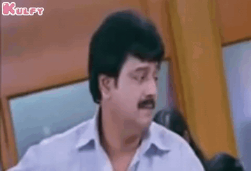 a man with a mustache is making a funny face while standing in a room .