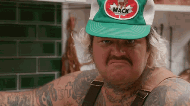 a man wearing a green hat with mack on it