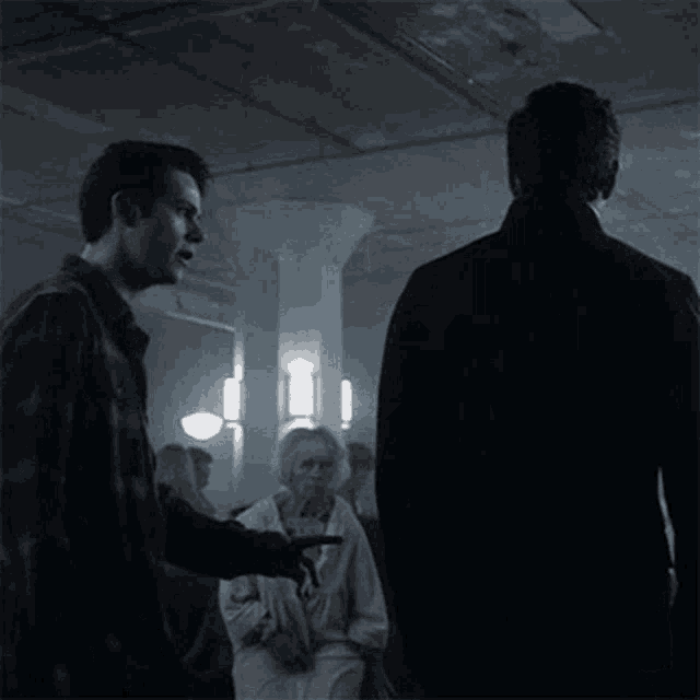 two men are standing next to each other in a dark room and one of them is asking the other how are you here ?
