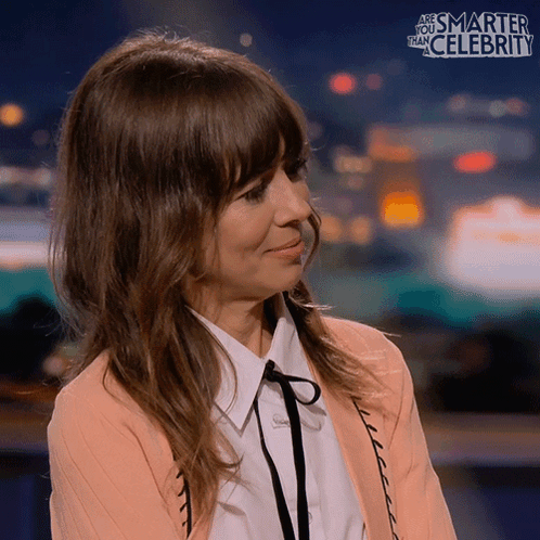 Natasha Leggero looks touched and smiles on a talk-show set.