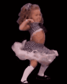 A tiny ballerina-like doll dances against a black background.