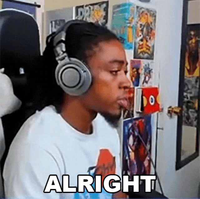 a man wearing headphones says alright in front of a wall full of posters