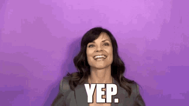 a woman is smiling and making a yep gesture against a purple background .