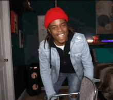 A person in a red beanie bends forward laughing in a room.