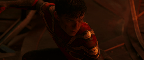 a man in a red and gold spiderman suit is looking down in a dark room