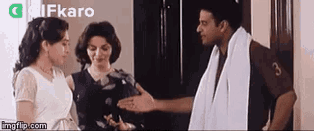 a man and two women are standing next to each other in a room and talking to each other .