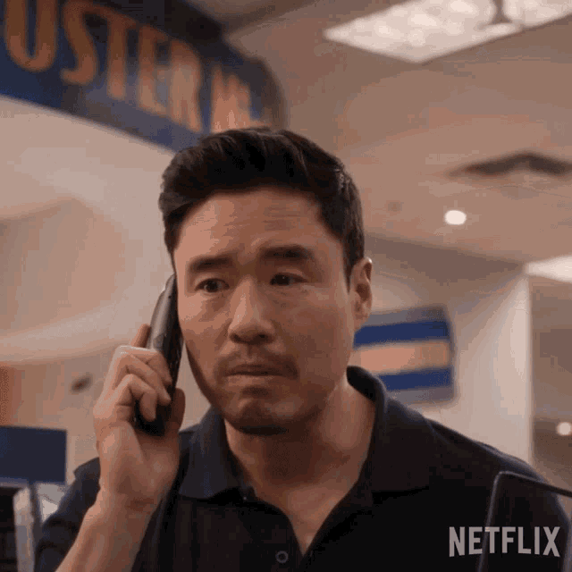 a man is talking on a cell phone in front of a sign that says netflix