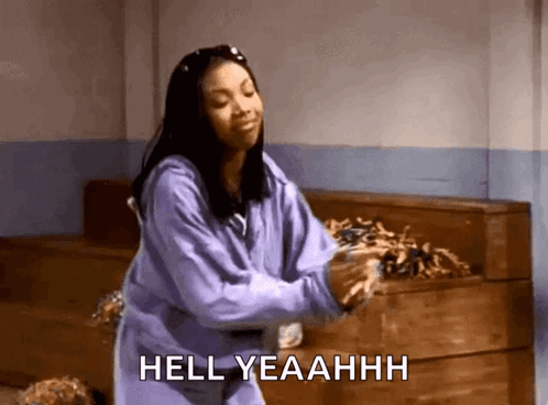 A woman in purple dances happily beside a piano with the caption “HELL YEAHHH”.