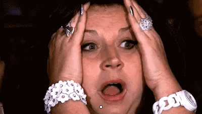 A distressed woman clutches her head with her mouth open.