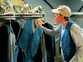 a man in a hat is looking at a clothes rack