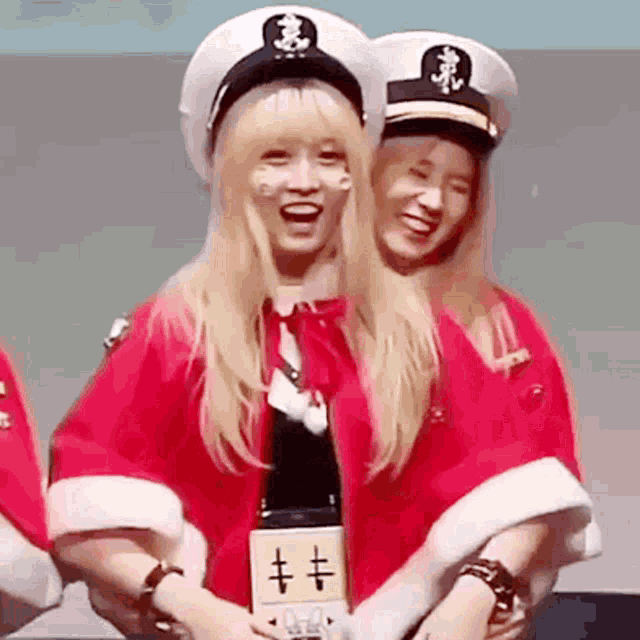 two blonde girls wearing captain hats are standing next to each other and smiling