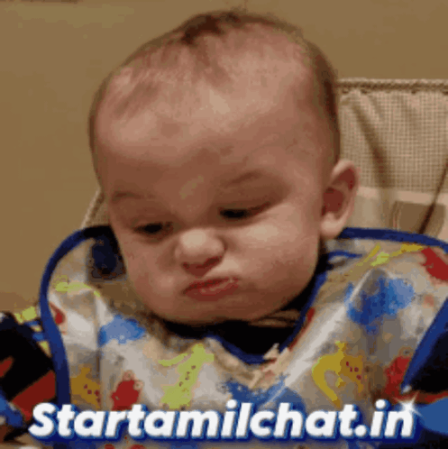 A baby looks down with a deep frown.
