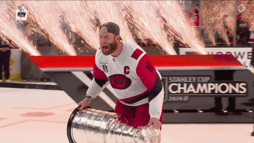 a hockey player holds a stanley cup in front of a sign that says champions