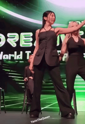 two women are dancing on a stage in front of a sign that says " world top "
