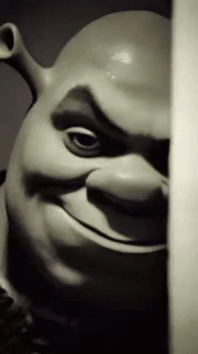 A dark close-up of Shrek peers from behind a doorway.