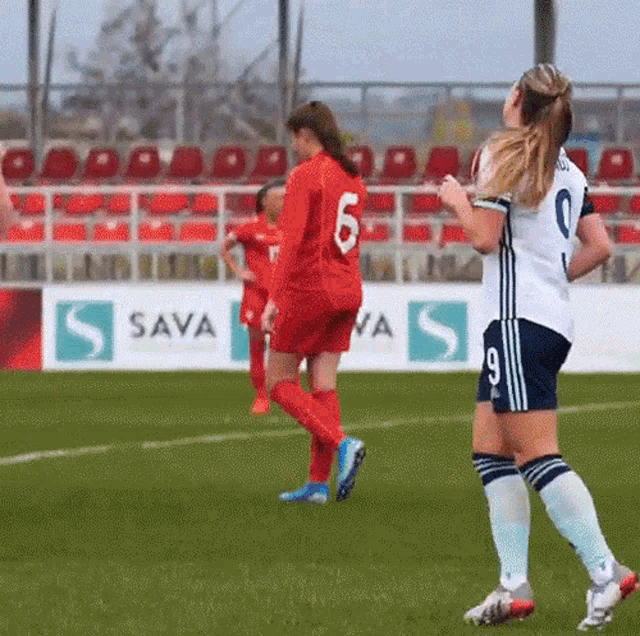 two female soccer players on a field with a banner behind them that says sava