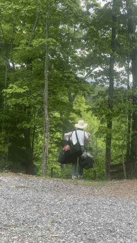 a person carrying a large bag on their back walking down a gravel road