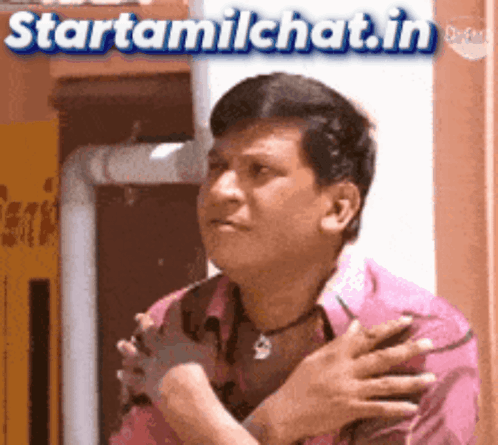 a man in a pink shirt has his hands folded in front of his chest ..