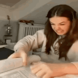 A young woman bends over a book or desk while studying.