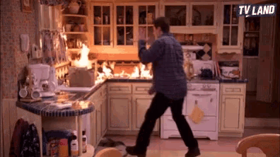 a man is walking through a kitchen with a fire coming out of the stove .