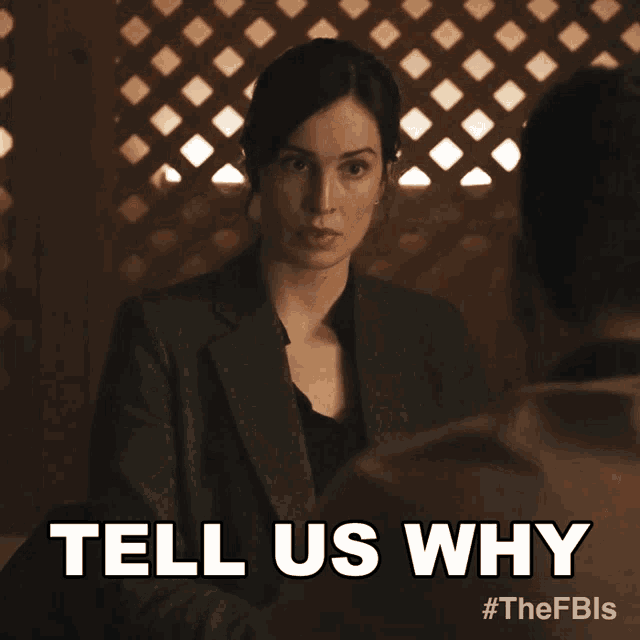 a woman in a suit is talking to a man and says tell us why
