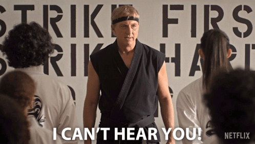 a man in a karate uniform is standing in front of a sign that says strike first