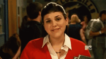 A woman in a red uniform reacts awkwardly in a crowded hallway.