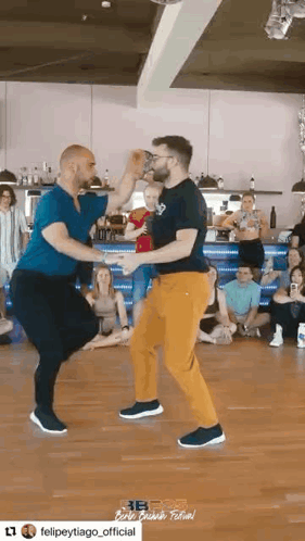 Two men perform a partnered bachata dance in a studio.