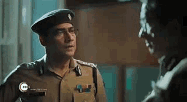 a man in a police uniform is talking to another man .
