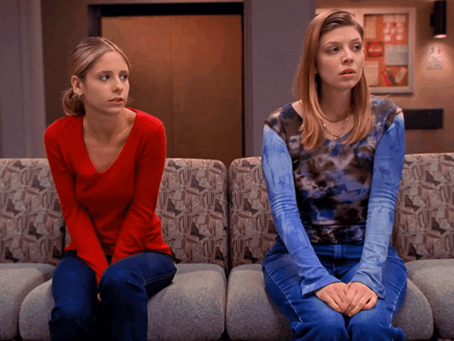 a woman in a red shirt sits next to another woman in a blue tie dye shirt