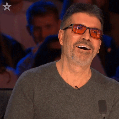 Simon Cowell grins with his mouth open in amazement.