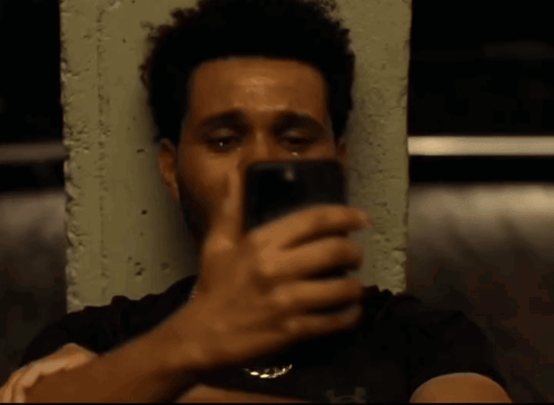 The Weeknd looks down at his phone with a subdued expression.