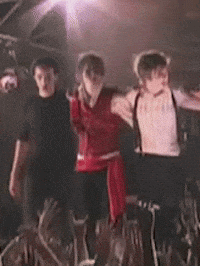 three people are dancing in front of a crowd at a concert .