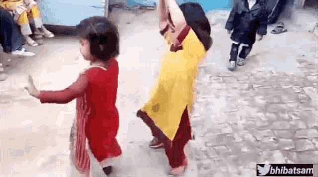 Two girls in red and yellow outfits dance in a snowy crowd.