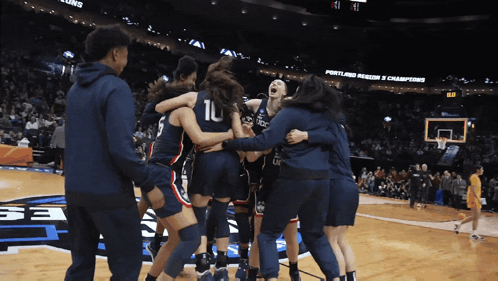 a group of female basketball players huddle on the court
