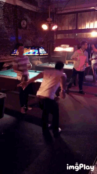 a group of men are dancing in a pool hall with a sign that says imgplay on the bottom