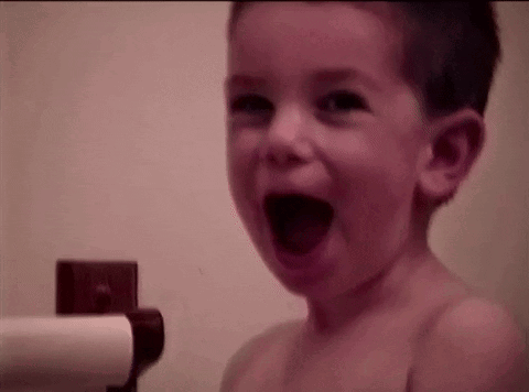 A young child laughs excitedly with mouth open.