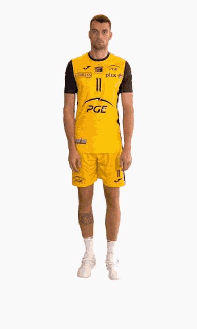 a man wearing a yellow pge shirt and shorts stands in front of a white background