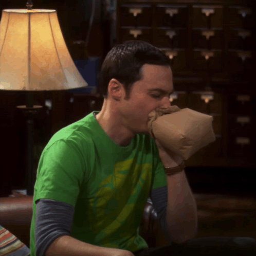Sheldon Cooper breathes rapidly into a paper bag in panic.