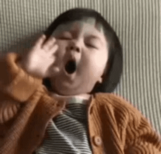 A young child yawns while holding a plush toy.