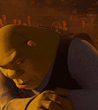 Shrek leans forward in a dark amber scene with a sly expression.