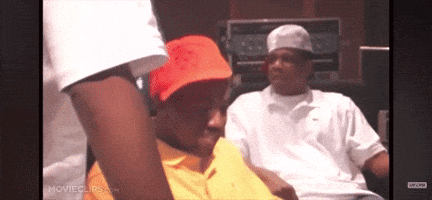a man in a yellow shirt is sitting next to another man in a red hat .