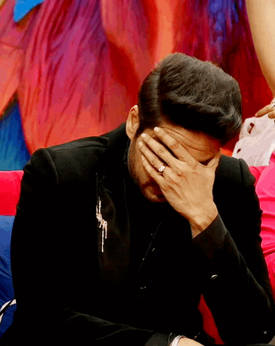 a man with a ring on his finger covers his face with his hand