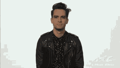 a man in a leather jacket and a floral shirt is making a sad face .