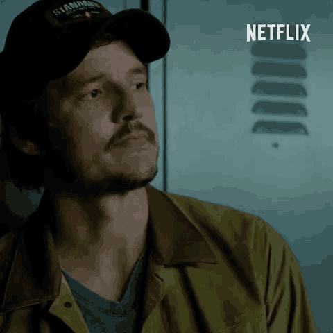 a man wearing a hat that says ' stanford ' on it stands in front of a netflix logo