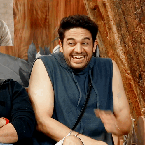 a man wearing a blue tank top is smiling and laughing