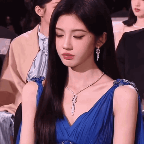 a woman in a blue dress is sitting in a crowd of people