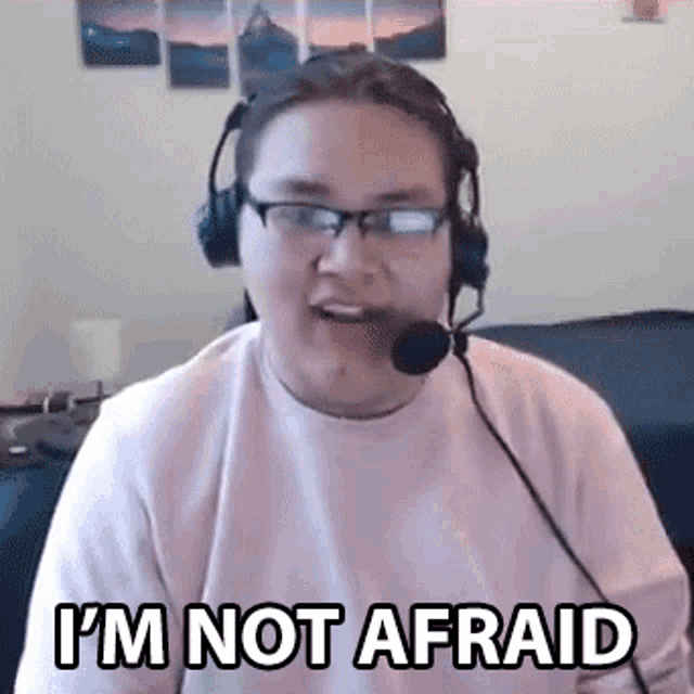 a man wearing headphones and glasses is making a funny face and saying `` i 'm not afraid '' .