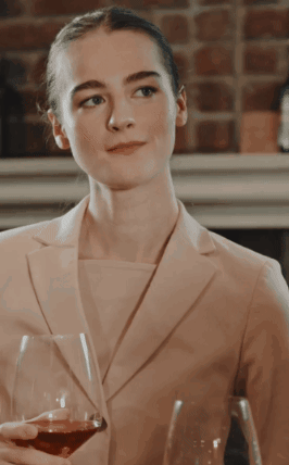 a woman in a suit is holding a wine glass